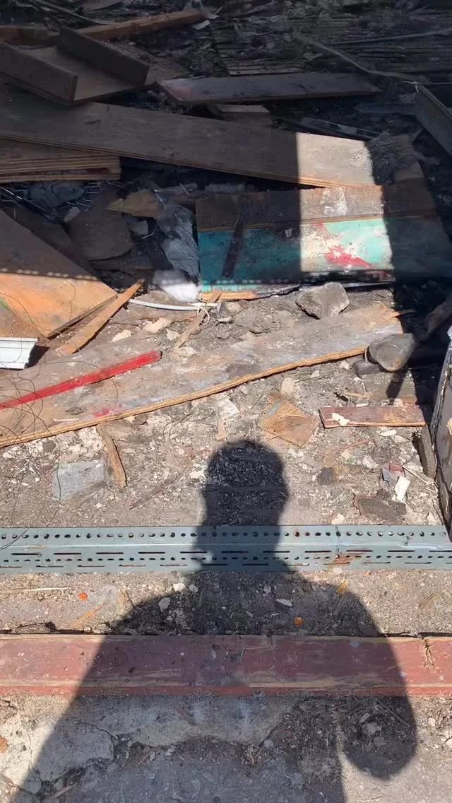 Charred lumber and fire debris at a burned structure assessed for smoke and soot contamination.