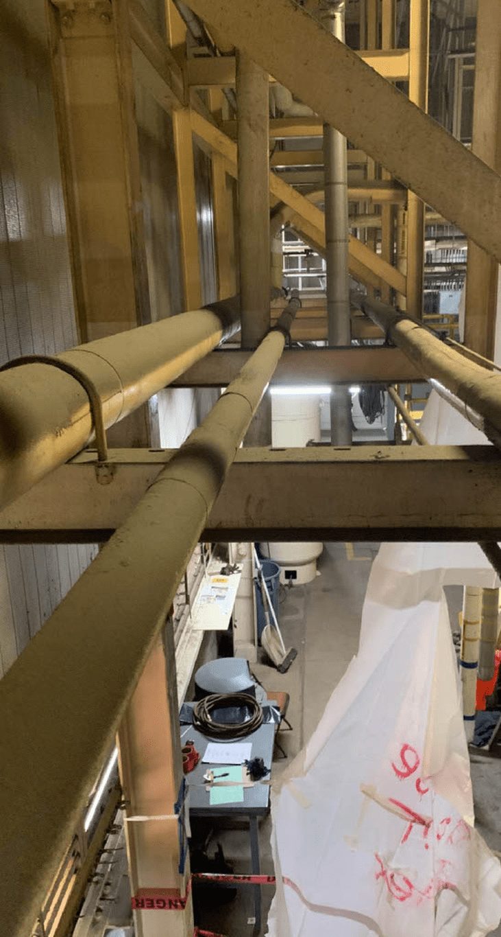 Asbestos containment sheeting and oversight inside an industrial plant, the building type left behind by Downey's aerospace manufacturing decades.